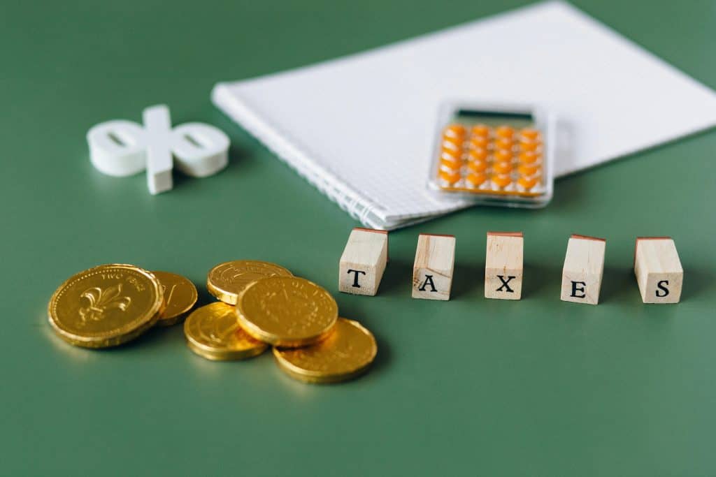 The word "TAXES" in bold block letters set against a bright green backdrop.